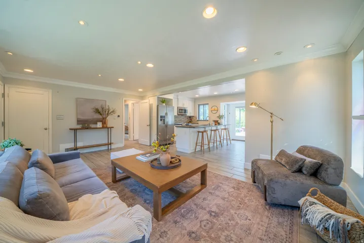Open-concept living area featuring recessed lighting, crown molding, and wood-finish flooring