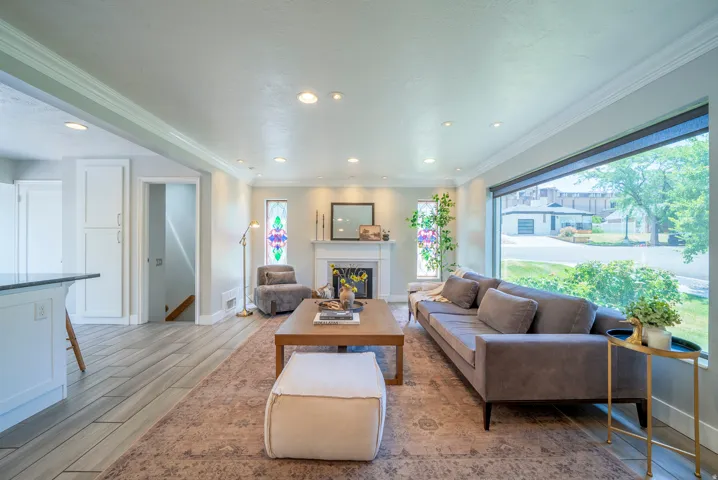 Spacious living area featuring a wide picture window, recessed lighting, and a white mantel fireplace