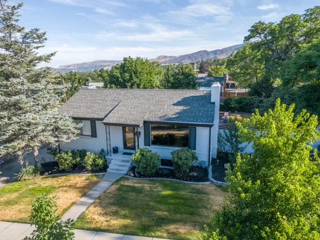 Ranch-style residence featuring a light-colored exterior with dark trim and a gabled roof