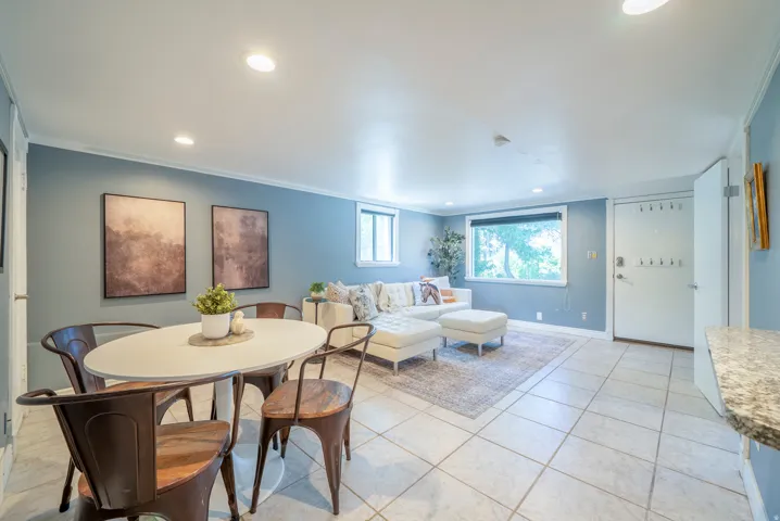 Open-concept living space featuring tiled flooring, recessed lighting, crown molding, and multiple windows
