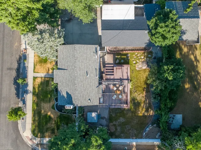 Expansive backyard featuring a multi-level wood deck, a pergola, a stone patio area, and mature perimeter trees