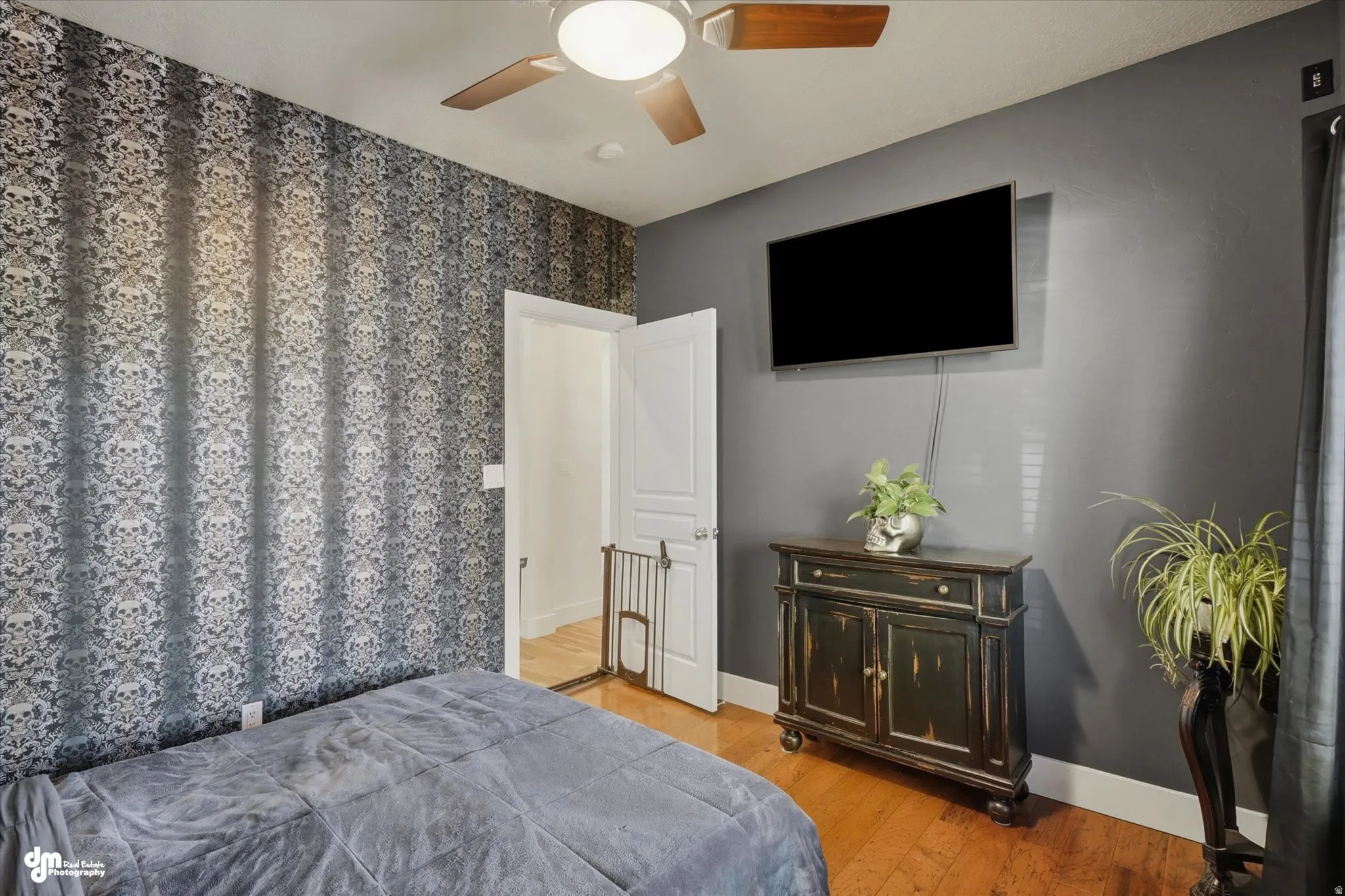 Bedroom featuring patterned wallpaper, wood-finish flooring, and a ceiling fan with integrated lighting