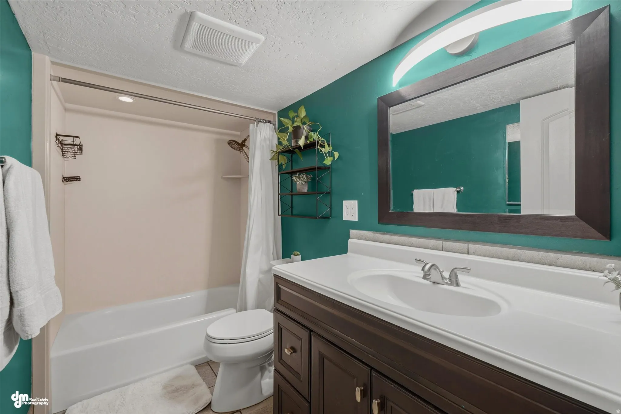 Bathroom featuring a wood-finish vanity with an integrated sink and brushed nickel faucet, a framed mirror, and a tub/shower combination with a showerhead