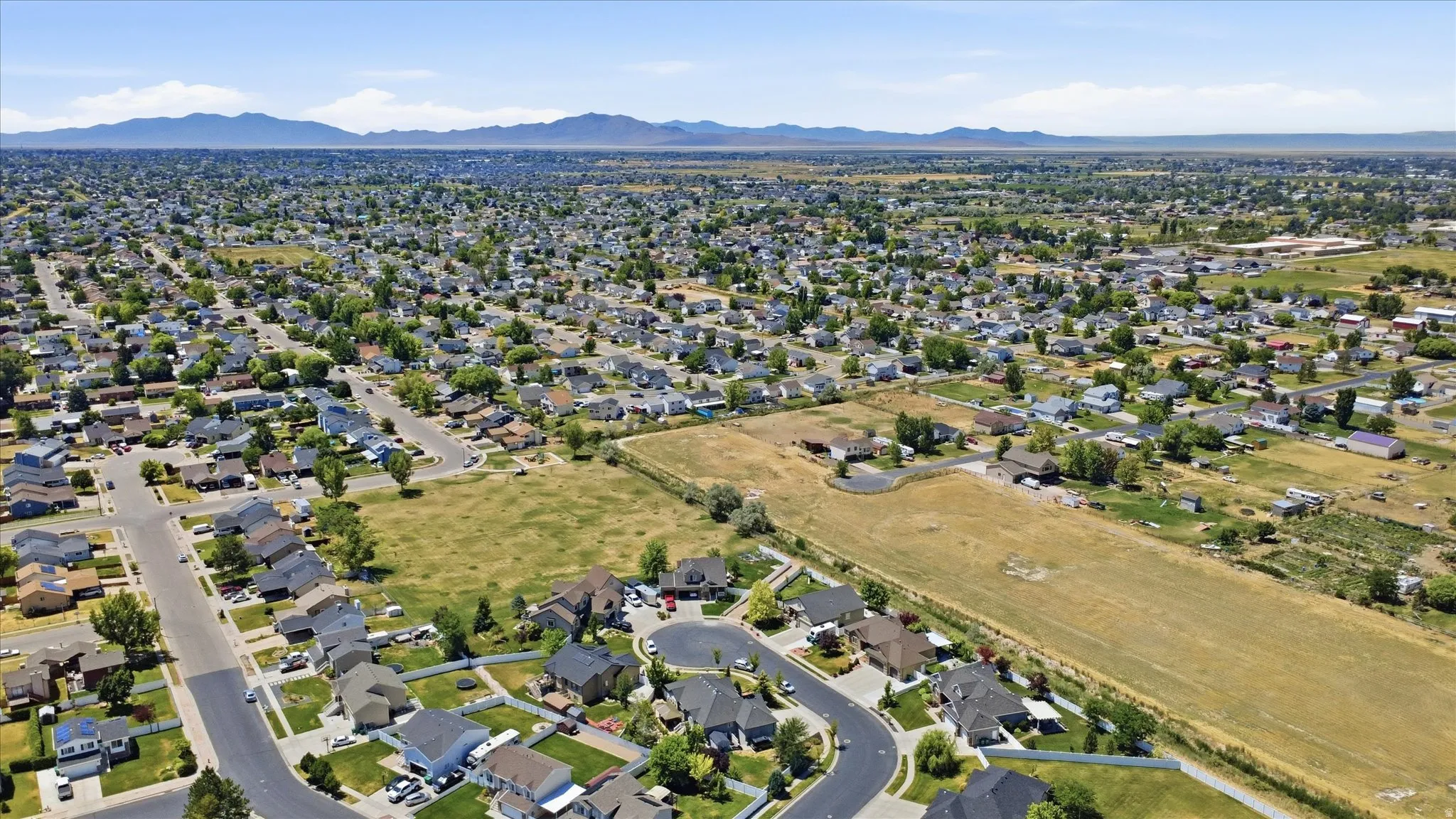 Expansive aerial perspective showcasing a residential development with established homes and undeveloped land