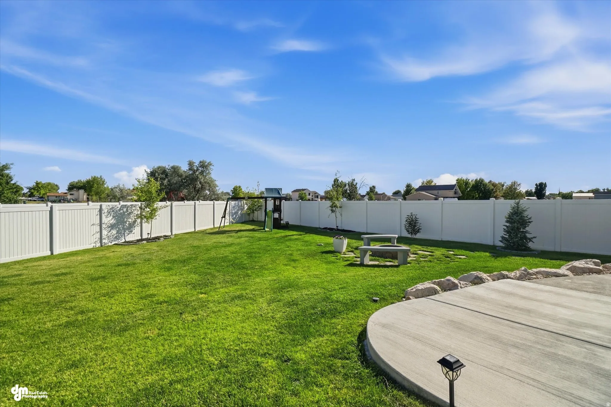 Expansive backyard featuring a lush lawn, privacy fencing, a concrete patio, and a dedicated garden area