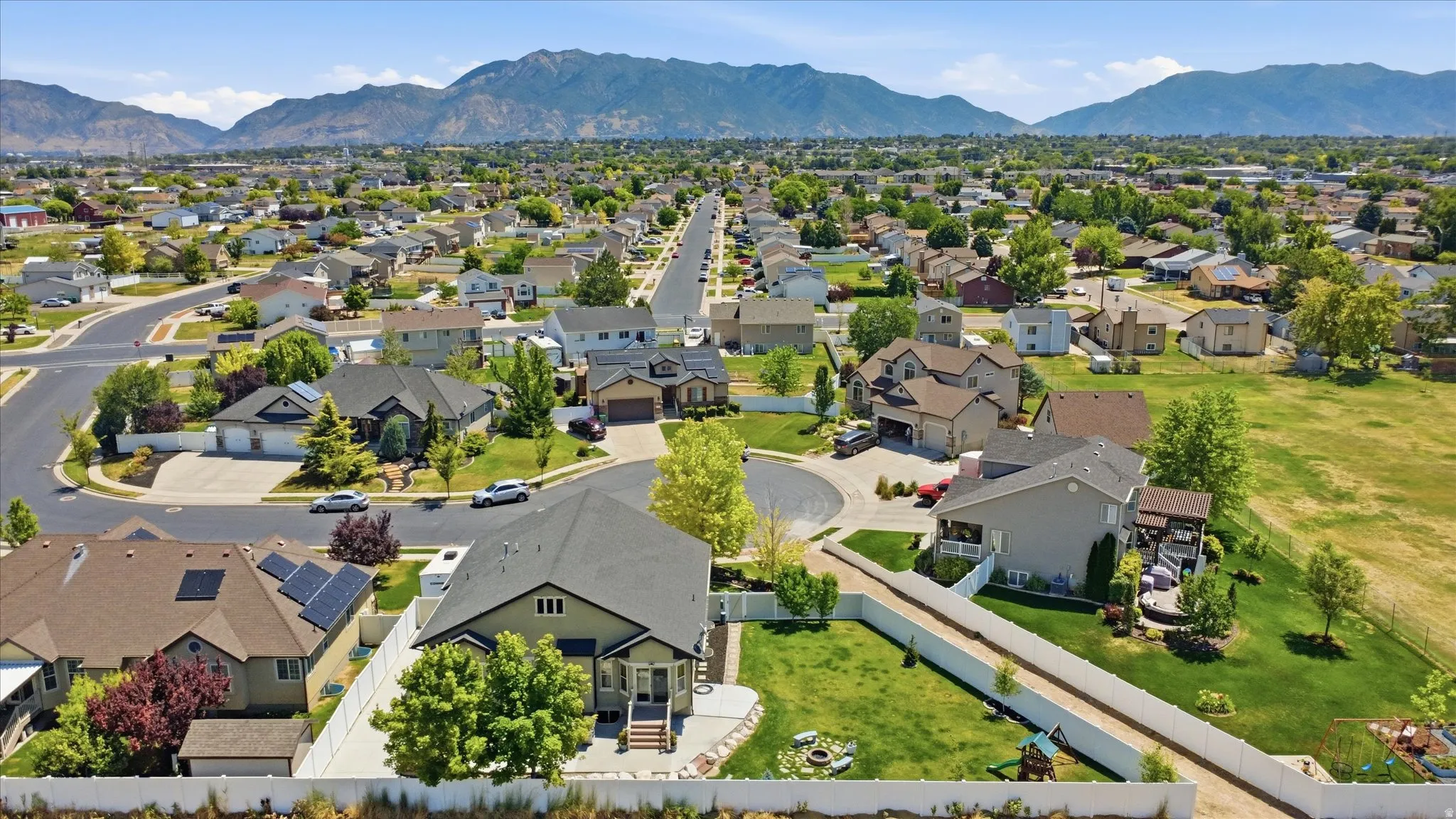 Residential neighborhood with varied architectural styles and mature landscaping against a mountain backdrop