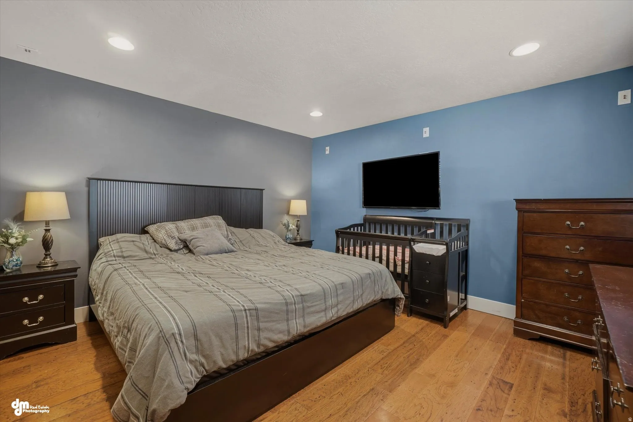 Spacious room featuring wood-finish flooring, recessed lighting, and a wall-mounted television