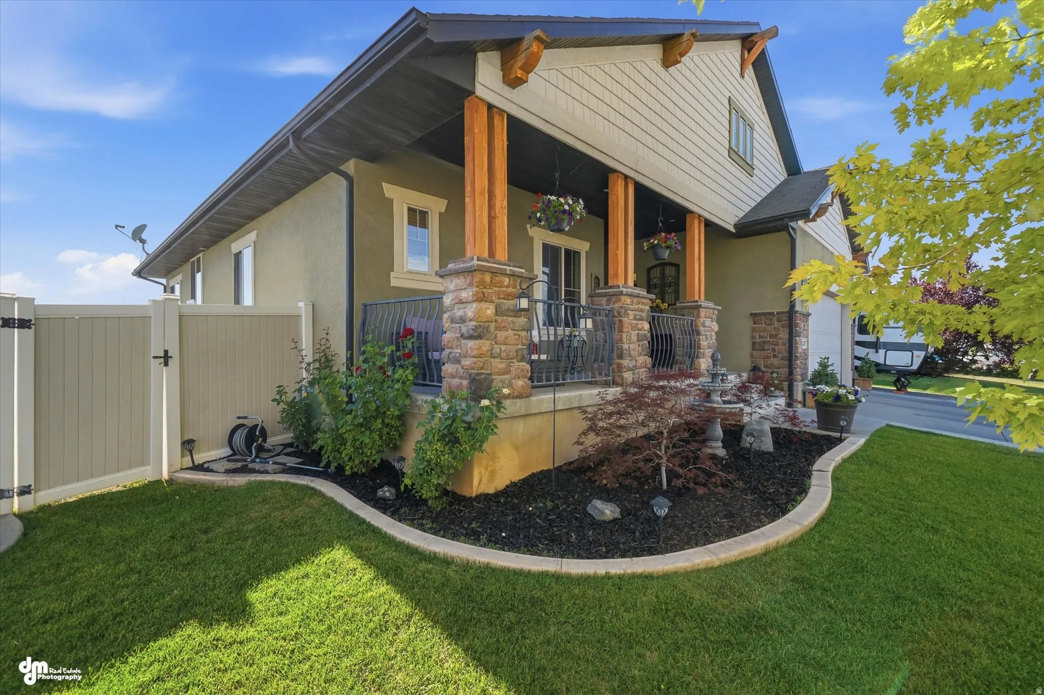 Front facade featuring a covered porch, stone columns, dark metal railings, and wood-finish support beams