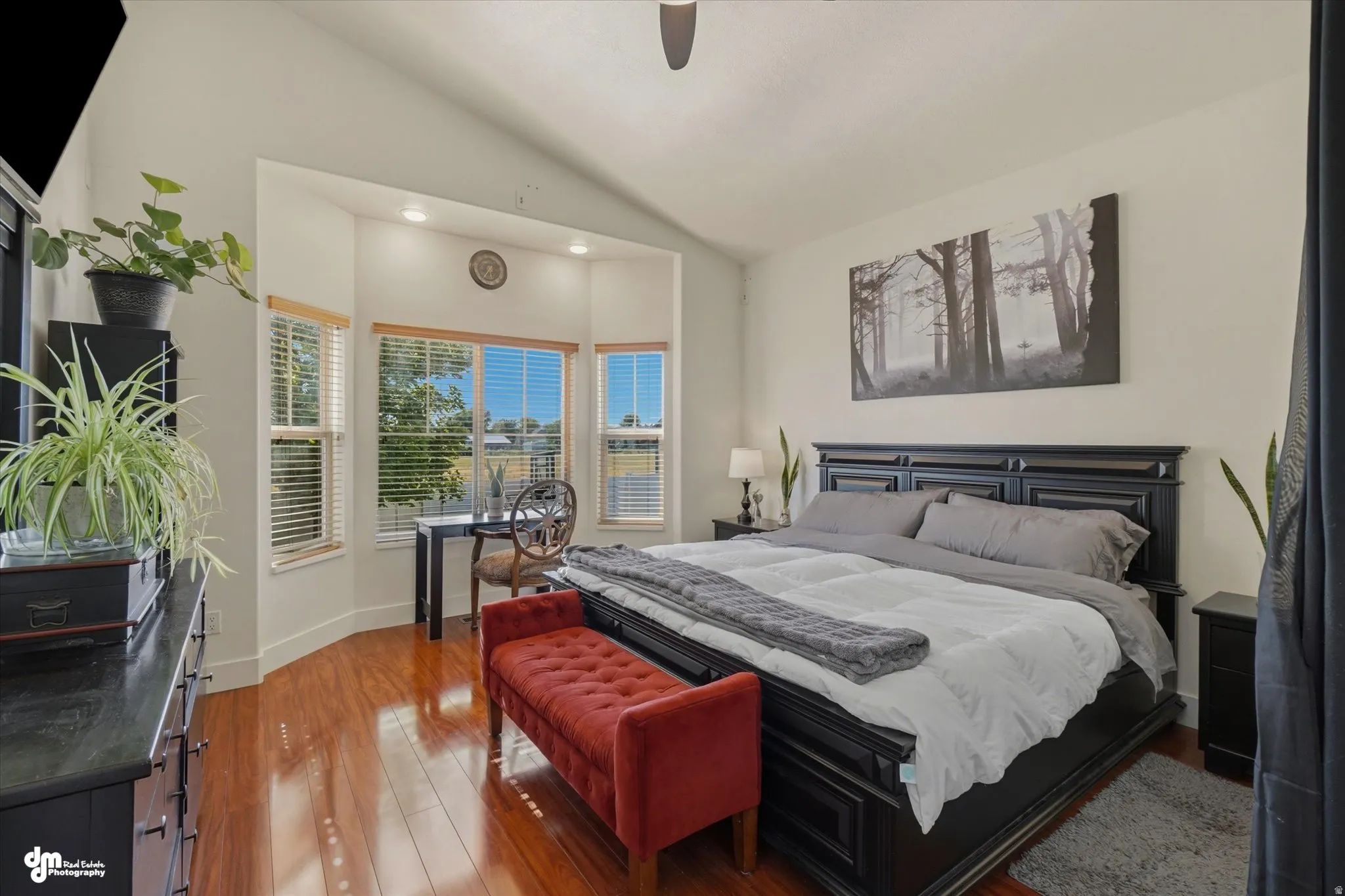 Angled vaulted ceiling with recessed lighting, wood-finish flooring, and a bay window featuring a built-in desk