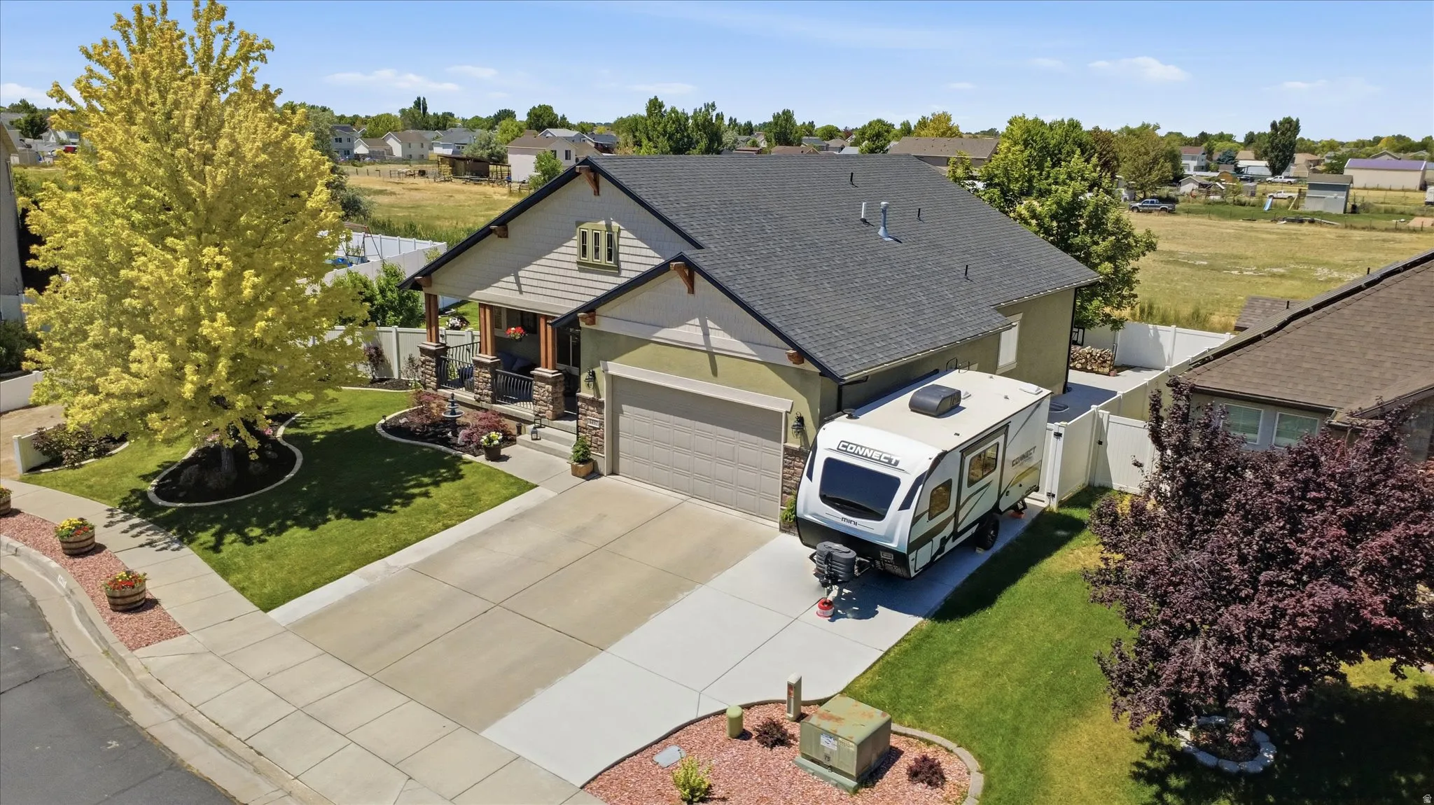 Two-story residence featuring a covered front porch with stone accents, a two-car garage, and an extended concrete driveway