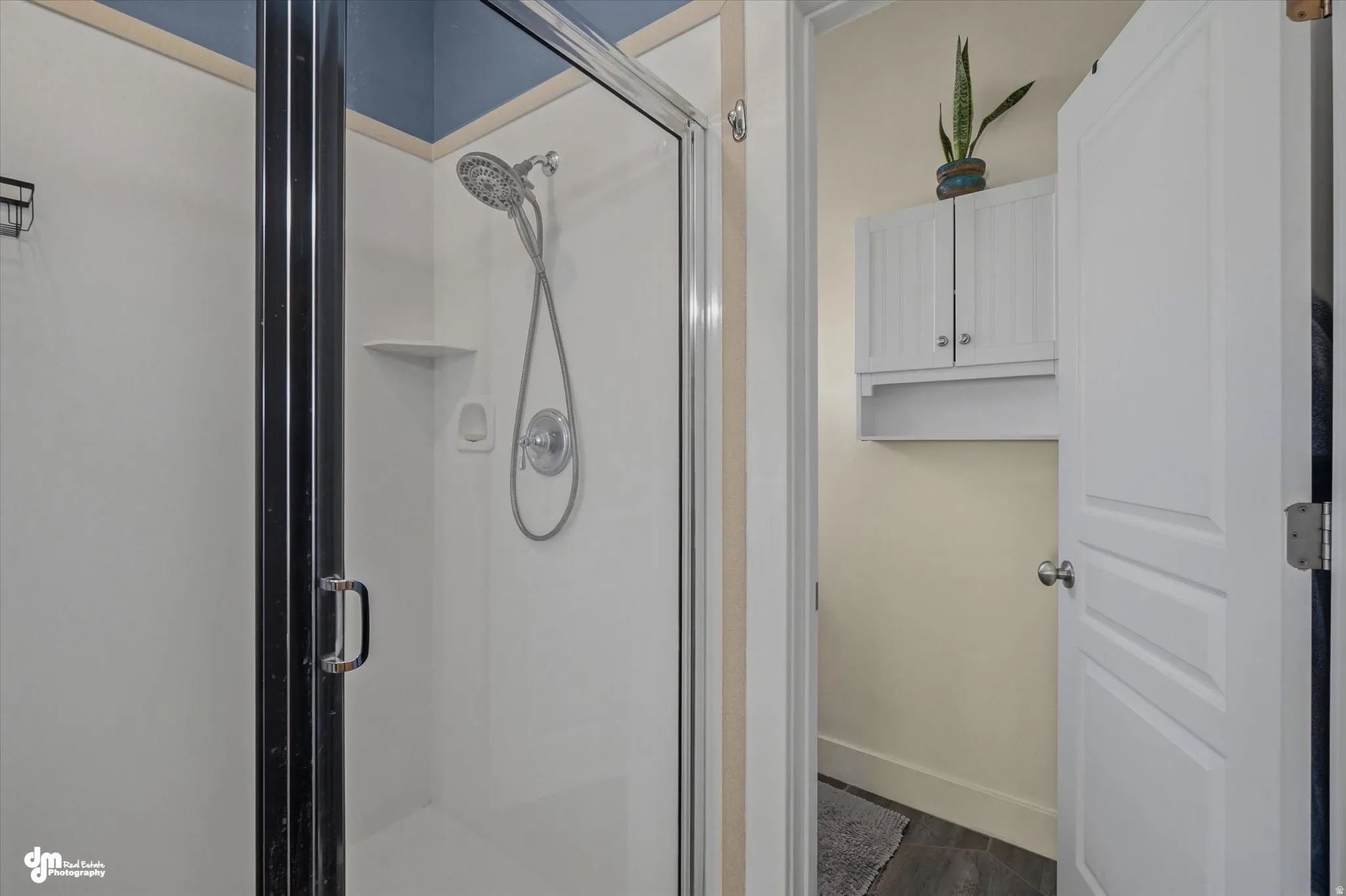 Shower enclosure with clear glass door and black framing, featuring a wall-mounted shower head and built-in shelving