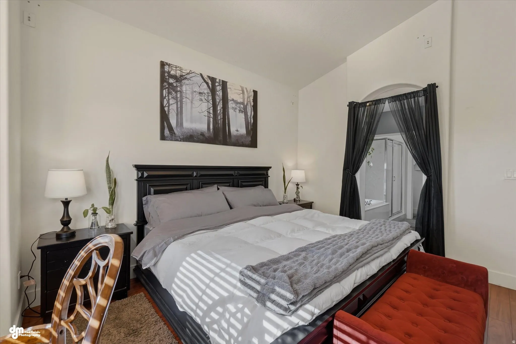 Spacious room featuring wood-finish flooring, an arched doorway, and recessed ceiling details