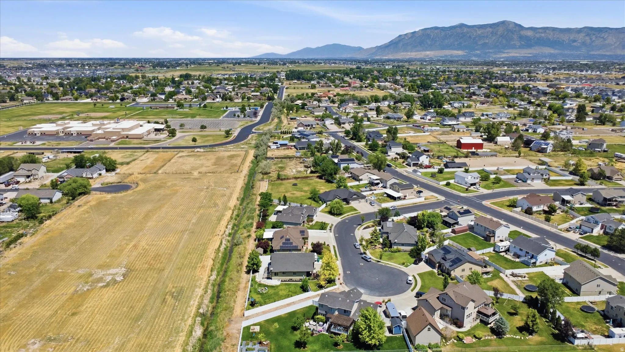 Expansive suburban landscape featuring a mix of residential properties, undeveloped land, and distant mountain ranges