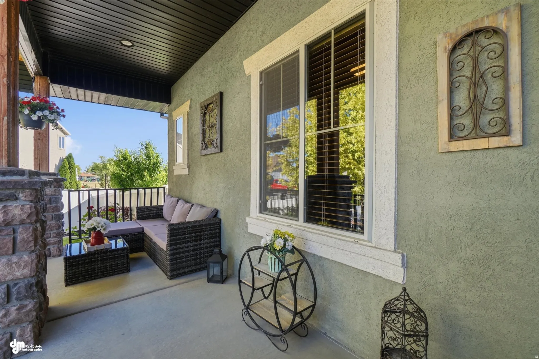 Covered porch featuring a stone-clad support pillar, stucco exterior, and a black vinyl soffit ceiling