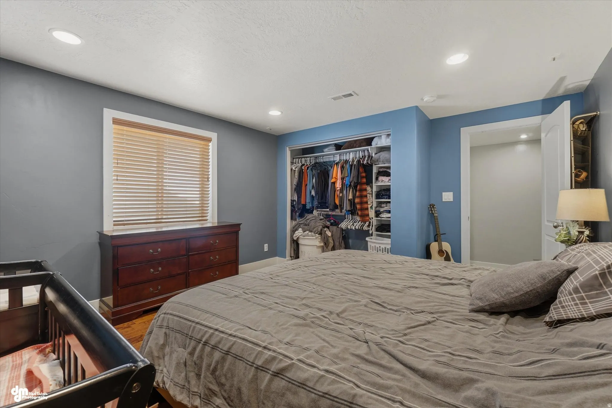 Spacious bedroom featuring wood-finish flooring, recessed ceiling lighting, and a window with blinds