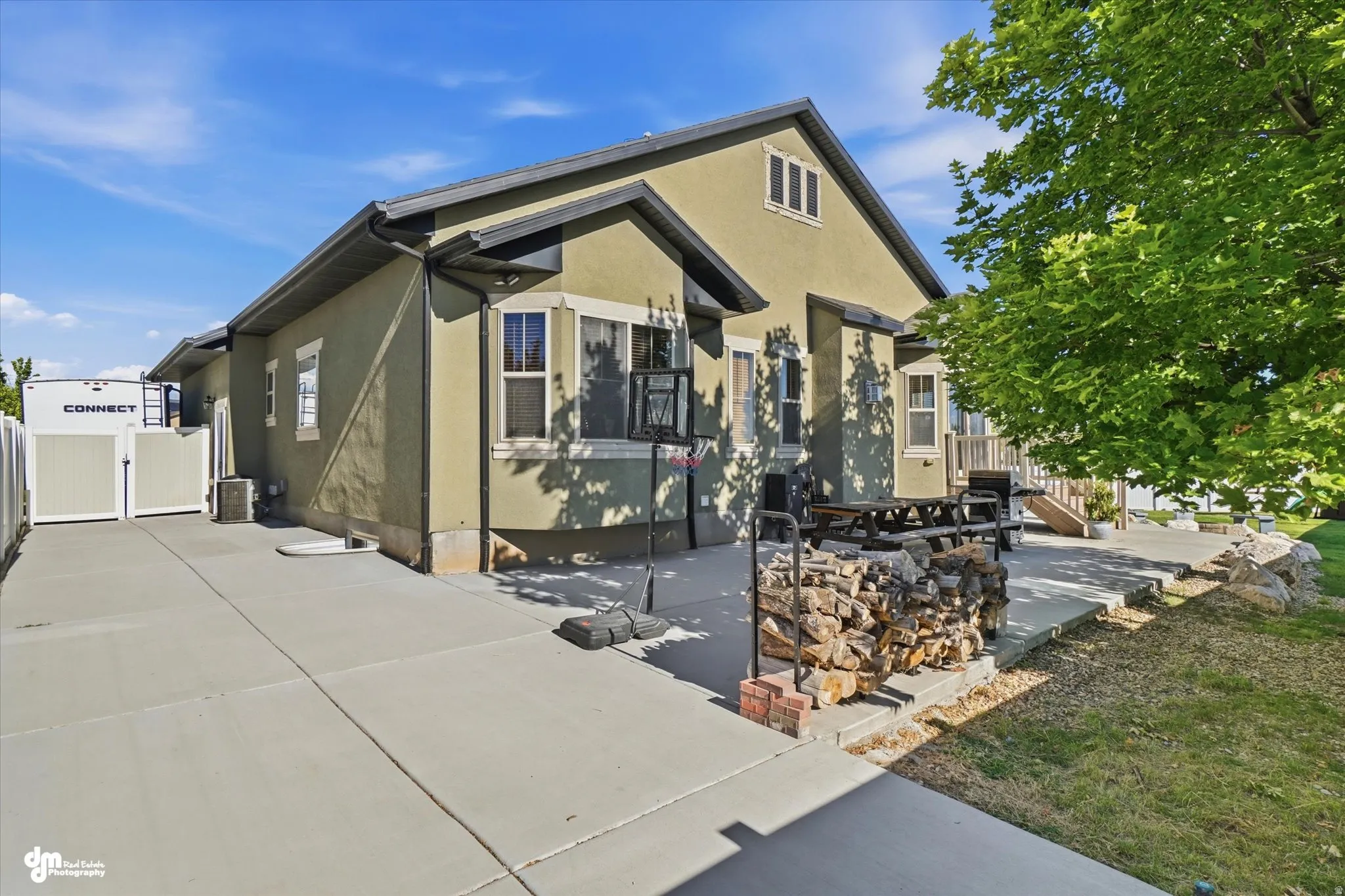 Expansive concrete driveway featuring a double gate, leading to a stucco-finish home with dark trim