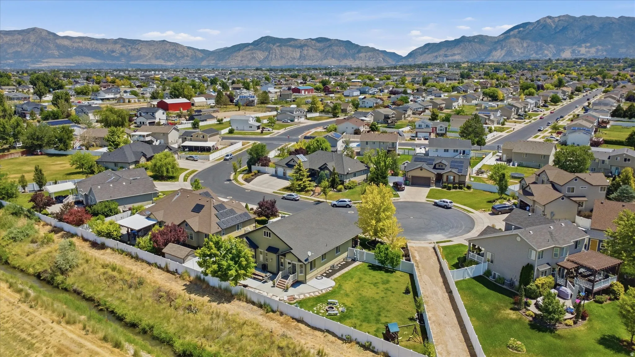 Suburban neighborhood with mature trees, mountain backdrop, and cul-de-sac