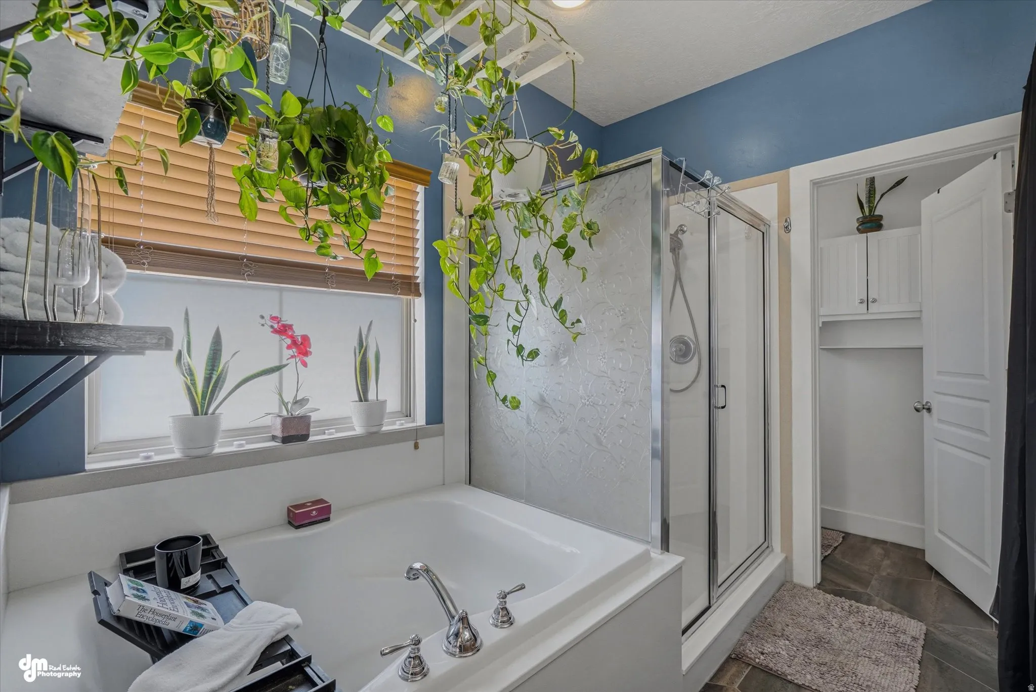 Bathroom featuring a built-in tub, a glass-enclosed shower with a brushed nickel showerhead, and window with wood-finish blinds