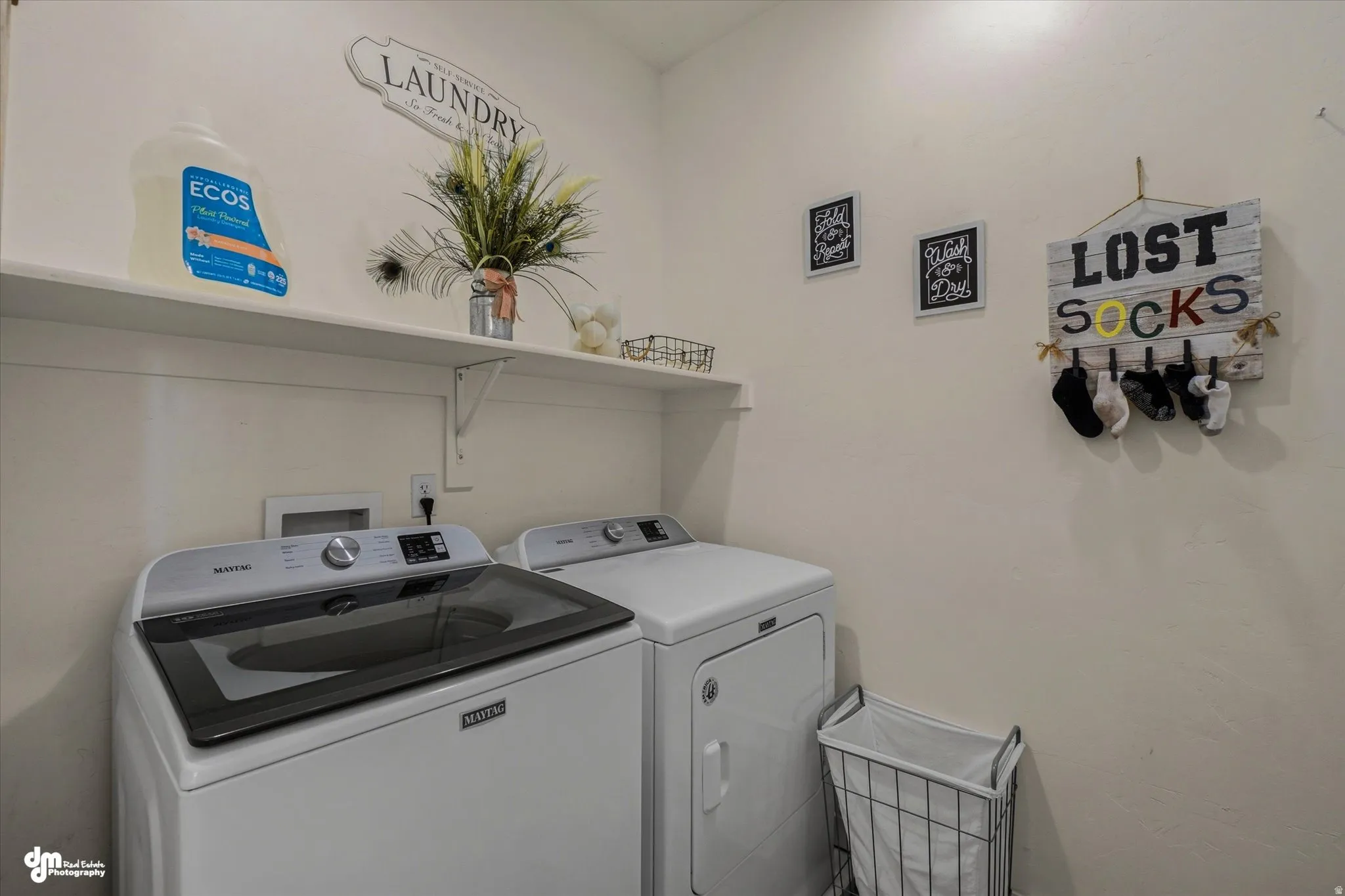 Laundry area featuring a top-load washer, front-load dryer, and two wall-mounted shelves for storage