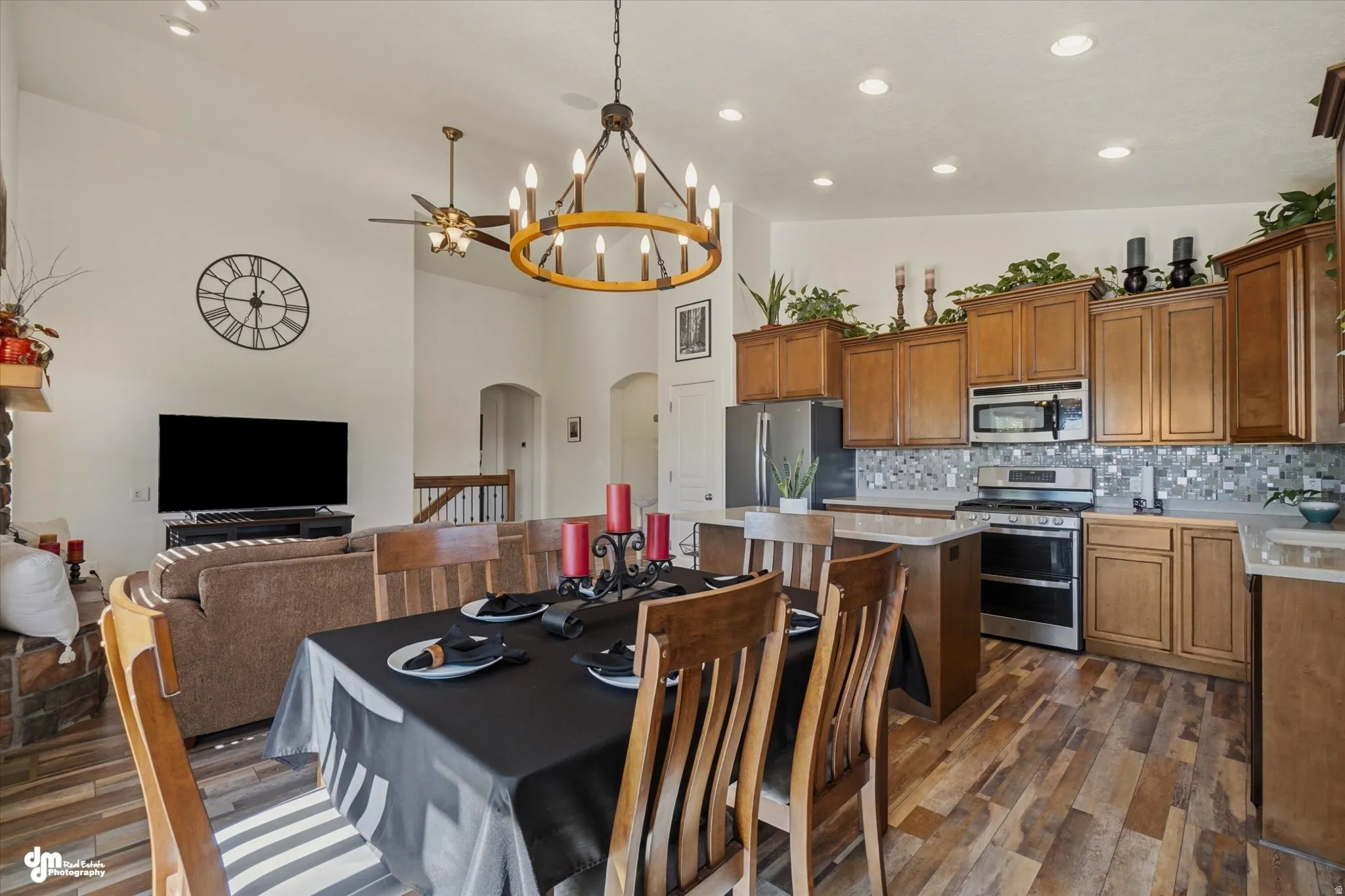 Spacious open-concept living area featuring a kitchen with wood cabinetry, stainless steel appliances, and a mosaic tile backsplash