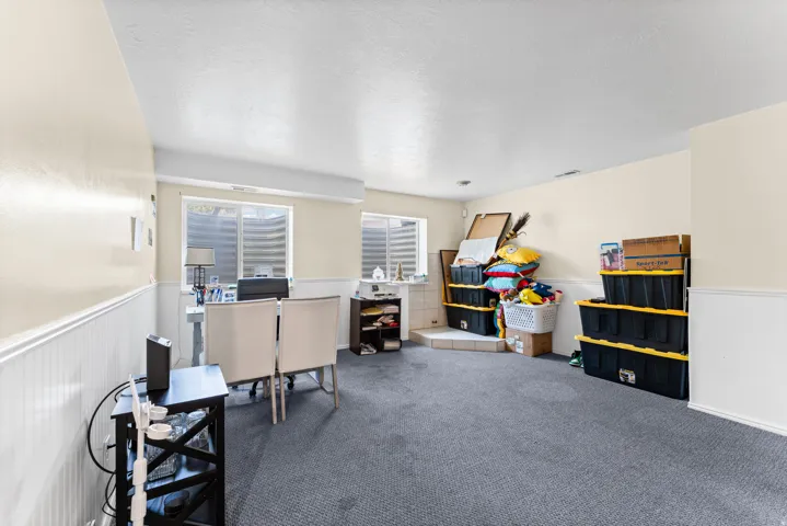 Spacious room featuring carpet flooring, dual egress windows, and wainscoting
