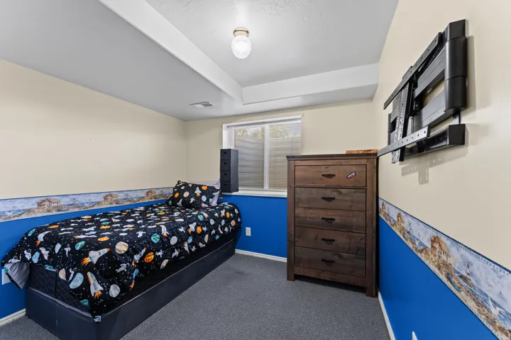 Carpeted room featuring a window with blinds, a ceiling-mounted light fixture, and a built-in wall mount for a television