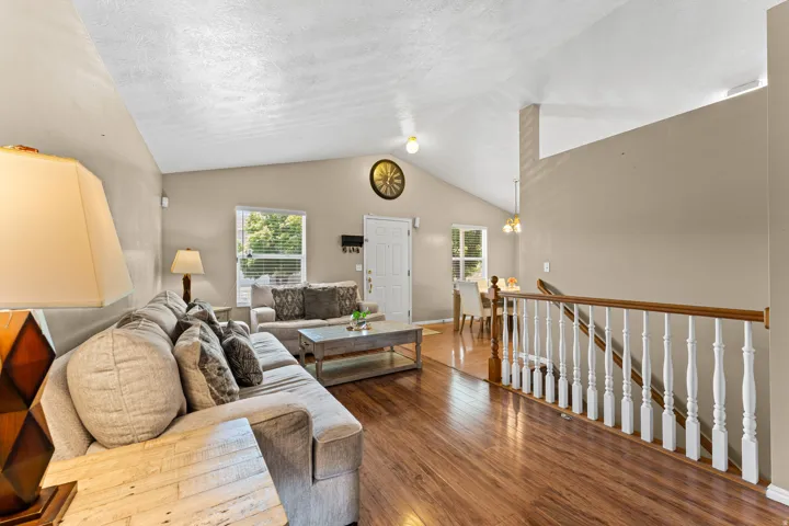 Living area featuring vaulted ceilings, wood-finish flooring, and neutral wall tones