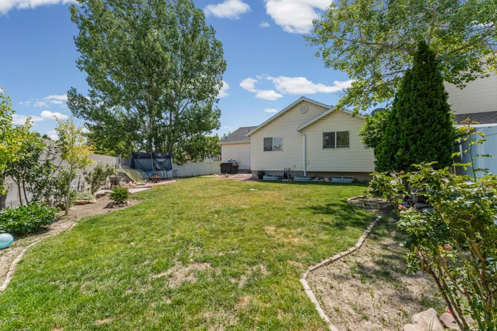 Expansive backyard featuring a large grassy area, mature trees, and landscaping beds with decorative edging