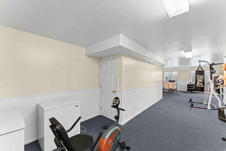 Spacious room with light-colored walls, white wainscoting, and a dark blue carpeted floor