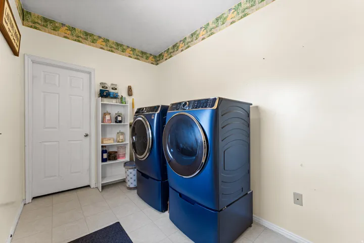 Utility room featuring tiled flooring, a built-in shelving unit, and a paneled door
