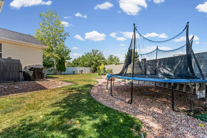 Expansive backyard featuring a manicured lawn, established perimeter fencing, and mature trees