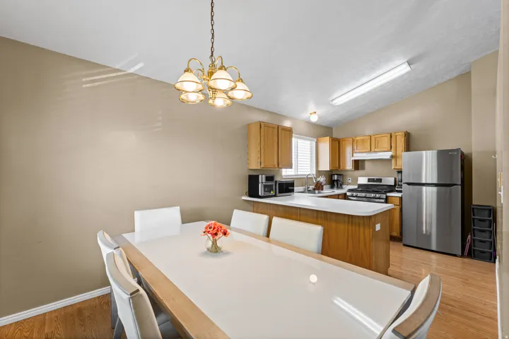 Kitchen and dining area featuring wood-finish flooring, a vaulted ceiling, and recessed lighting