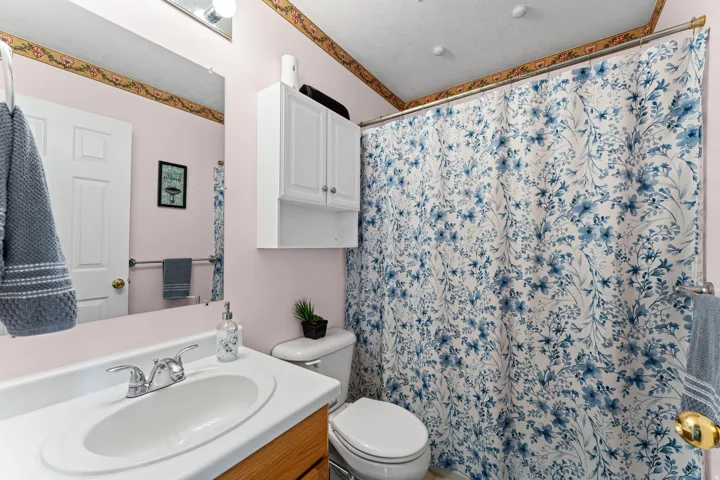 Bathroom featuring a single vanity with wood-finish cabinetry, a white countertop, and a chrome faucet