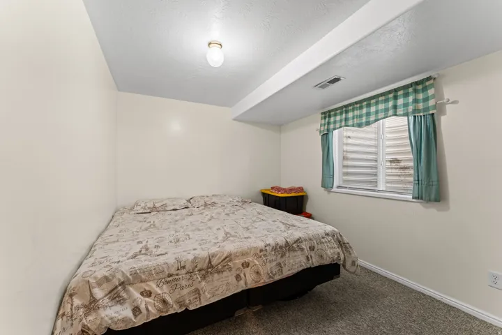 Carpeted room featuring a single window with a window well, white baseboards, and overhead lighting