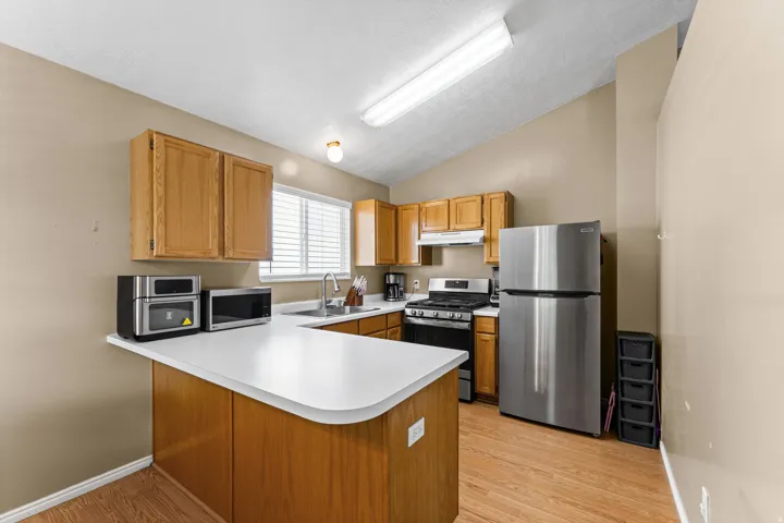 Kitchen featuring wood-finish flooring, a white countertop peninsula, and light wood cabinetry