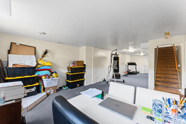 Lower-level recreation room with carpeting, recessed lighting, and wainscoting
