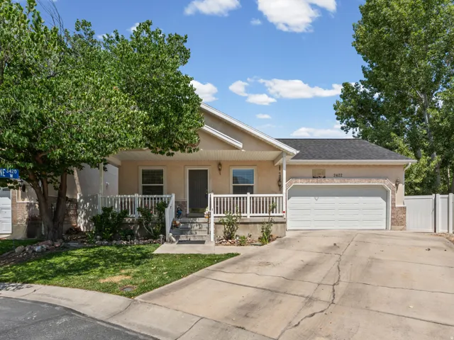 Single-story residence featuring a two-car garage, front porch with white railing, and a durable asphalt shingle roof