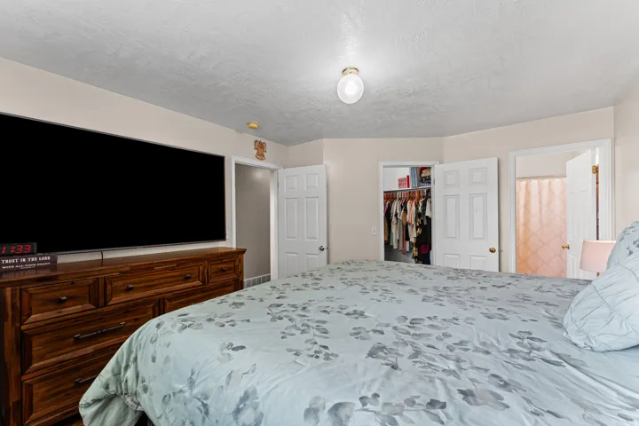 Bedroom featuring two paneled doors, one leading to a closet with hanging storage and the other to a full bathroom