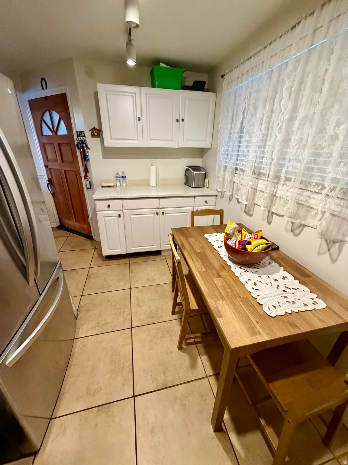 Kitchen area featuring tile flooring, white cabinetry, and a light-toned wooden dining table