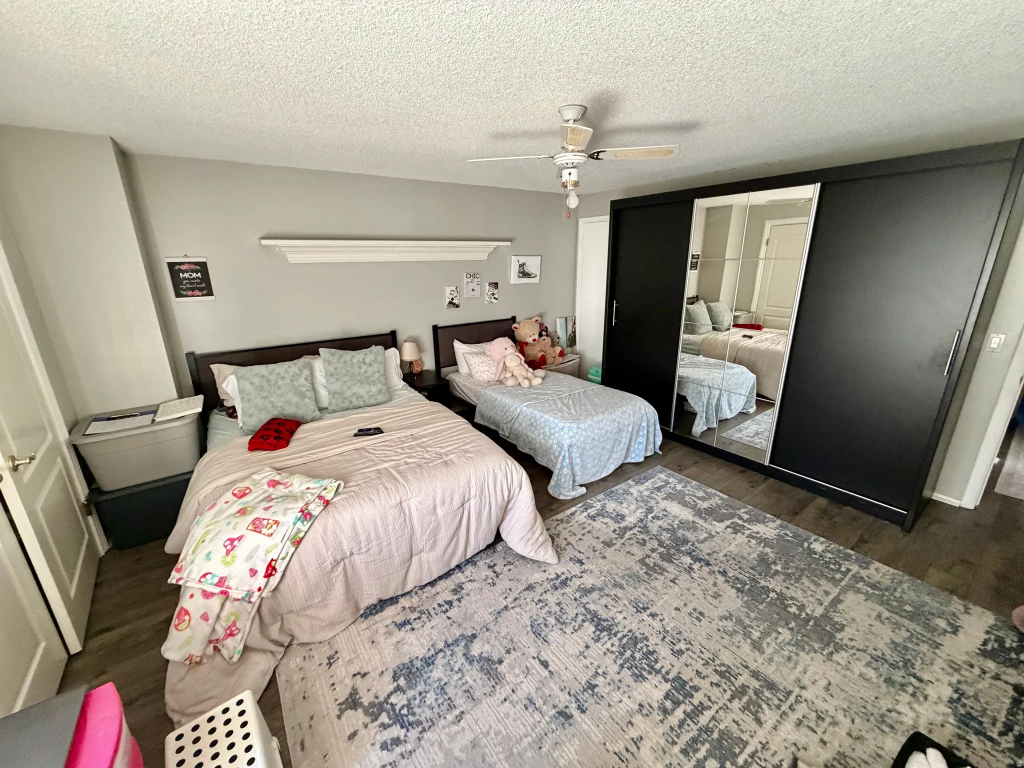 Spacious room with dark wood-finish flooring, light gray walls, and a ceiling fan