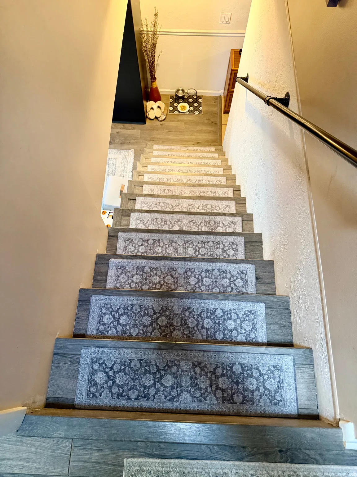 Wood-finish staircase featuring individual patterned stair runners and a wall-mounted metal handrail