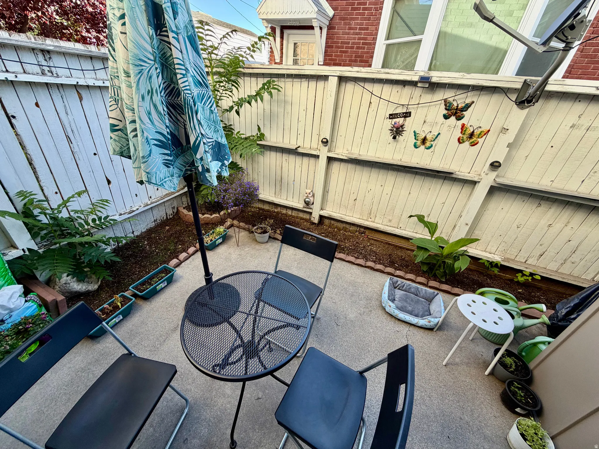 Patio space featuring concrete flooring, a wooden privacy fence, and planted garden beds