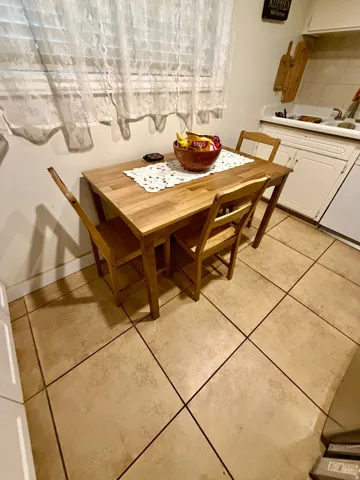 Kitchen area featuring light-toned tile flooring, white cabinetry, and a window with blinds