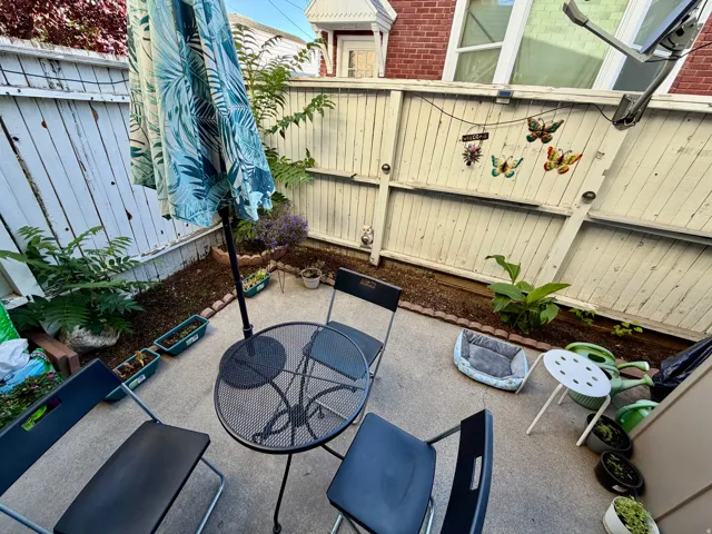 Patio space featuring concrete flooring, a wooden privacy fence, and planted garden beds