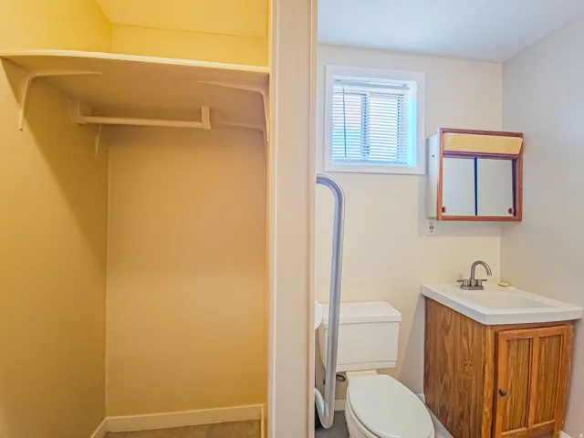 Bathroom with a wood-finish vanity, integrated sink, and window with blinds