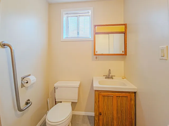 Powder room featuring a corner vanity with a wood-finish cabinet, white basin, and silver-tone faucet