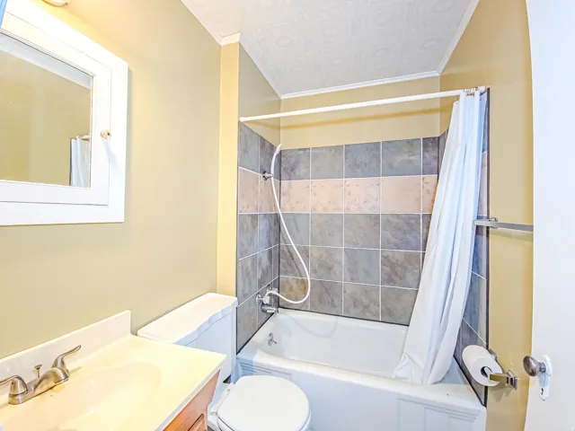 Bathroom featuring a shower-over-tub combination with multi-tone tile surround, a built-in vanity with integrated sink, and a mirrored medicine cabinet