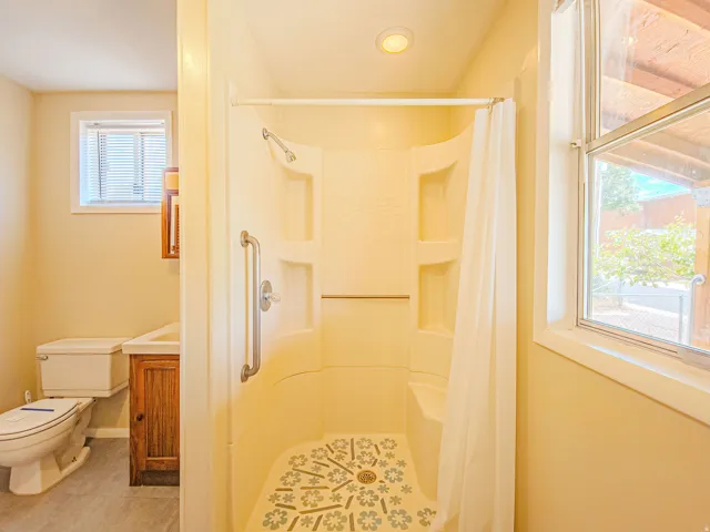 Bathroom featuring a built-in shower with integrated seating, a decorative floor pattern, and a grab bar