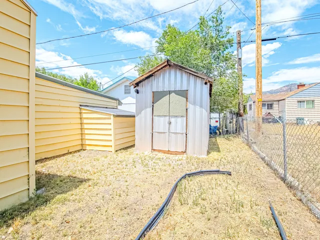 Rear yard featuring a corrugated metal utility shed and chain link perimeter fencing