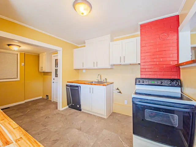 Kitchen featuring white cabinetry, wood-finish countertops, and a tile floor